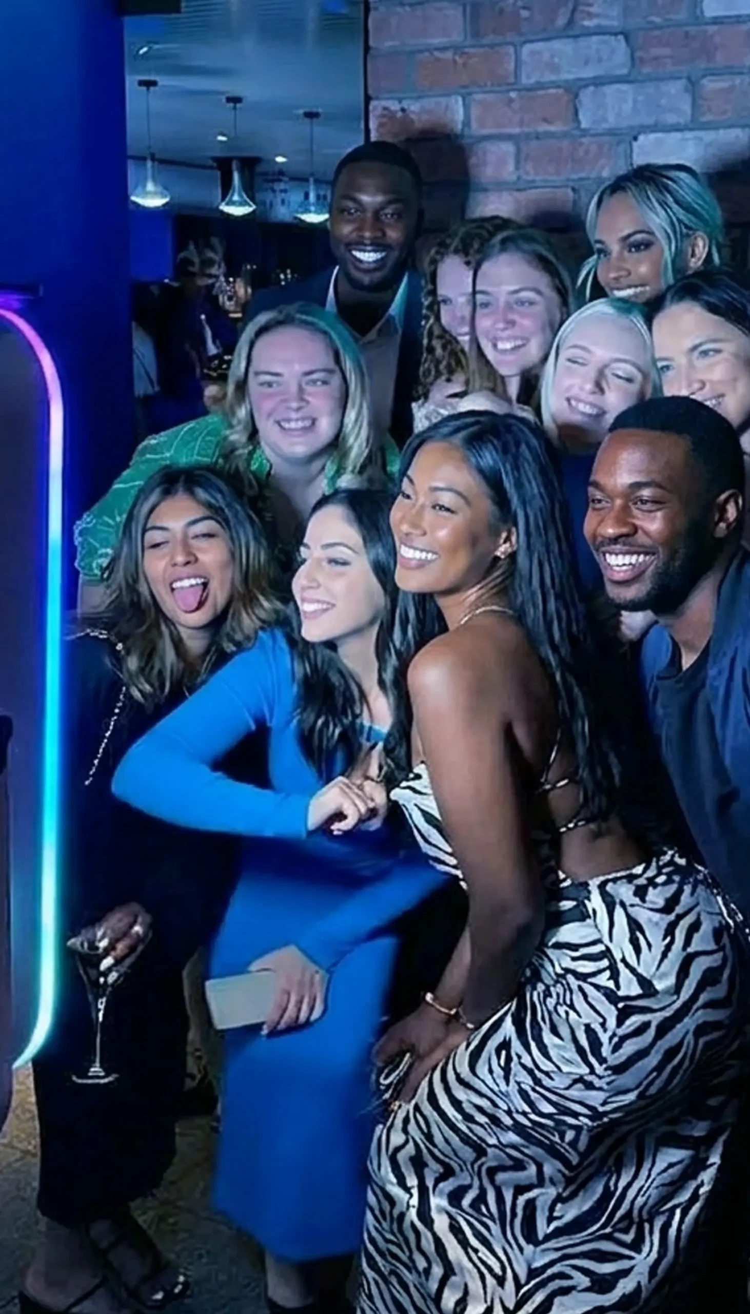Large group of guests posing at an open-air photo booth with RGB LED lighting at an upscale Phoenix event — Ooh La La Booths photo booth rental Arizona